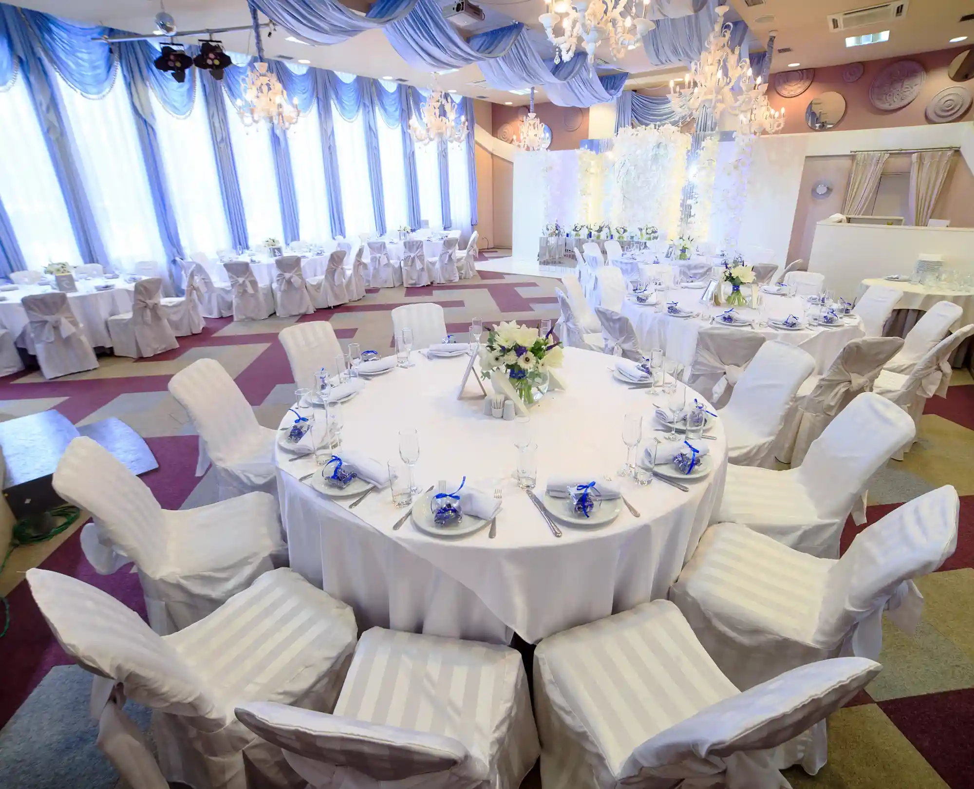 white covered round table surrounded by white covered chairs
