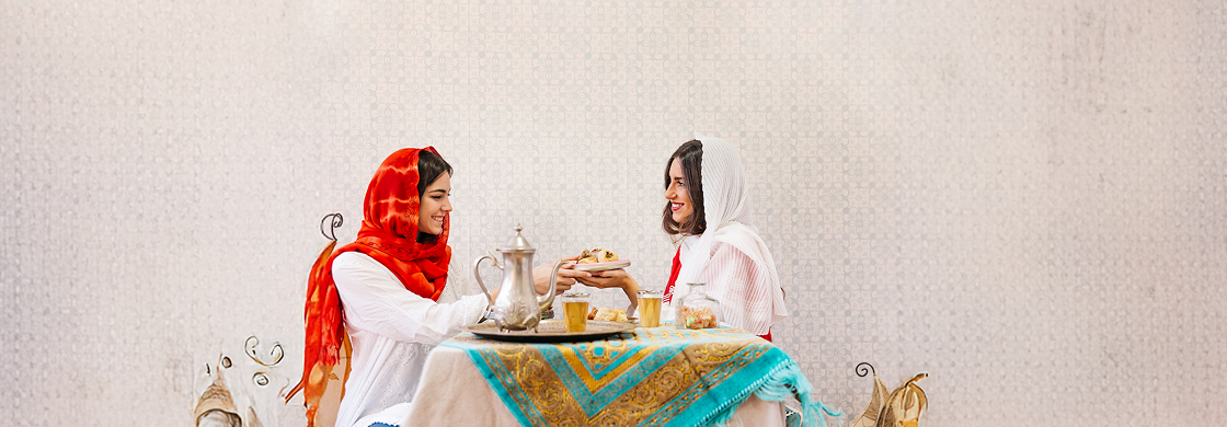 two young Muslim women are sitting in front of a table