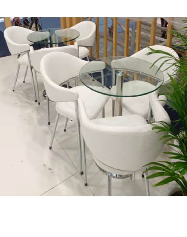 two round glass table surrounded by three white chairs each